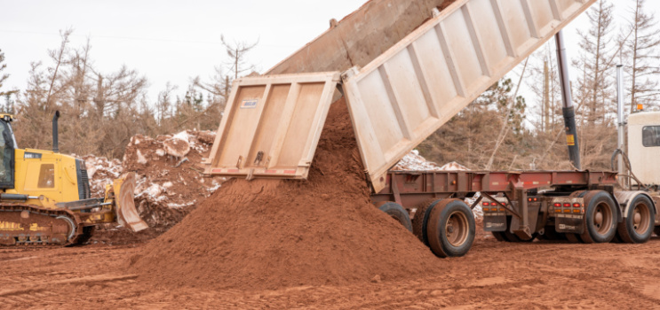 A dump truck at work loading red dirt at Cedar Dunes Provincial Park