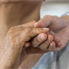 Health care worker holding elderly woman's hand