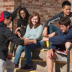 Group of high school students sitting outside on steps to school