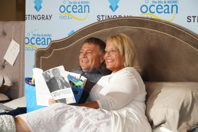 image of two people smiling and reading a book sitting together on a couch