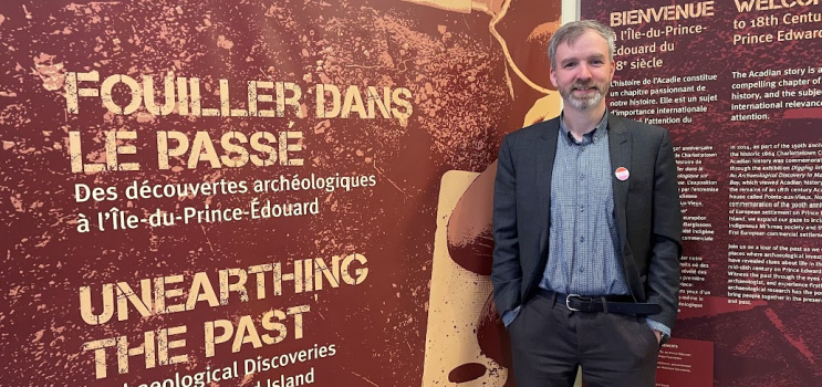 Matthew McRae standing in front of exhibit sign