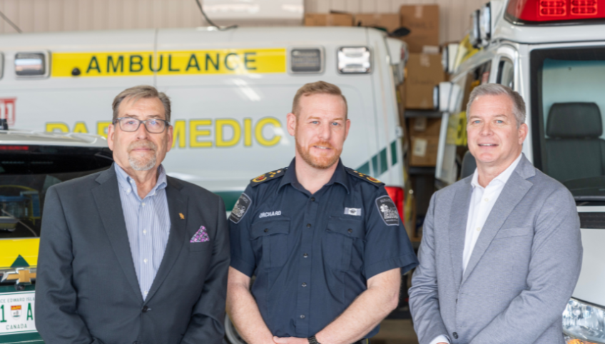 image of three people standing shoulder to shoulder in front of some ambulance emergency vehicles