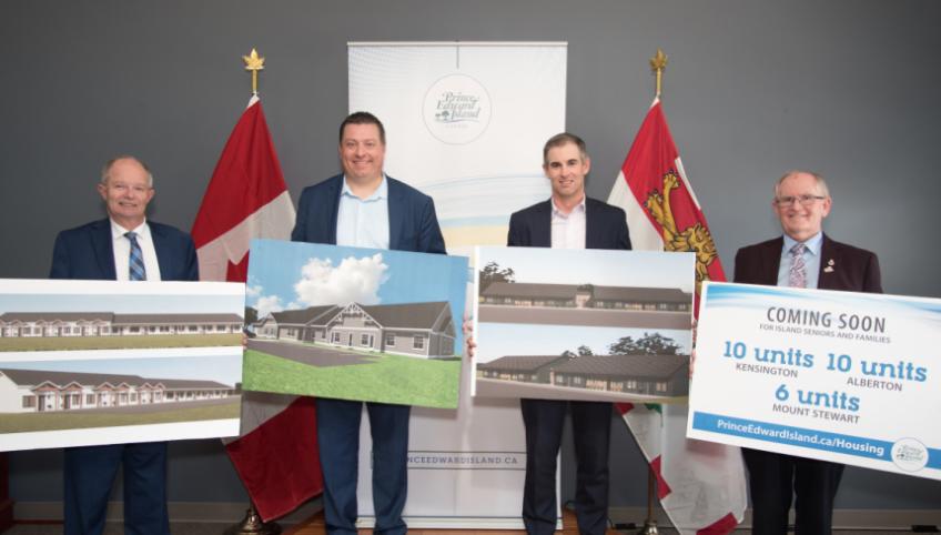 image of four people standing shoulder to shoulder holding sketches of new housing units