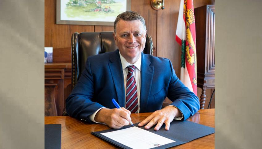 image of a man sitting at a desk signing a document