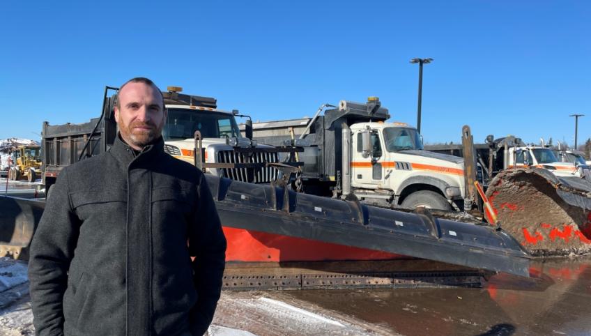 Stephen Szwarc, Director of Highway Maintenance, standing beside truck plows