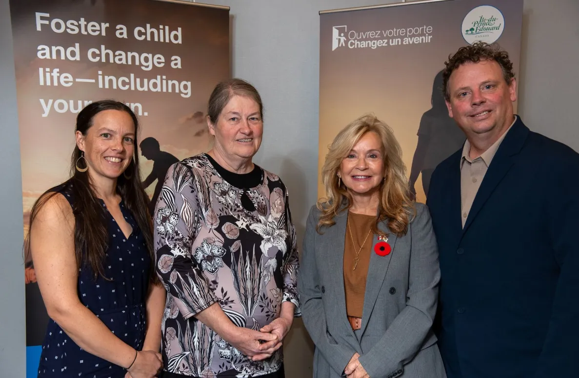 Trois femmes et un homme se tiennent devant les affiches de la campagne de parrainage.