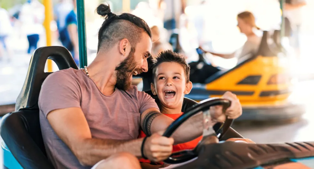 Man and a little boy in a bumper car at an amusement park