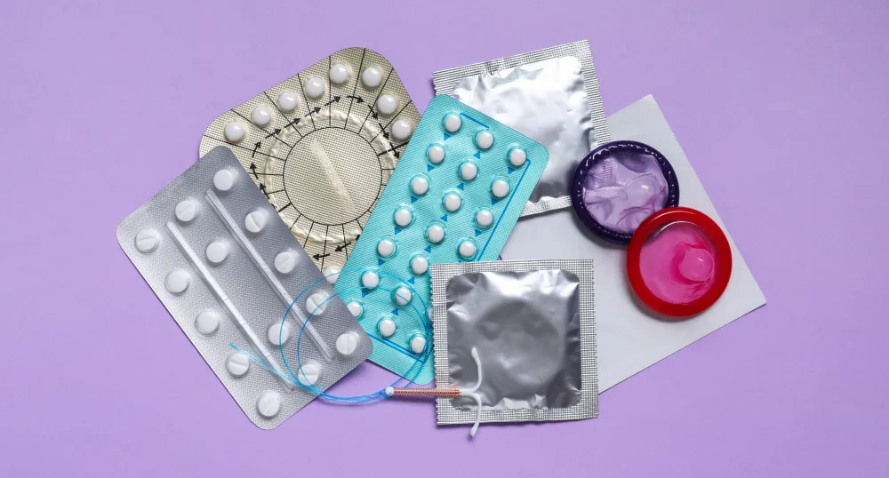 Different contraceptives laid out together with a lilac backdrop.