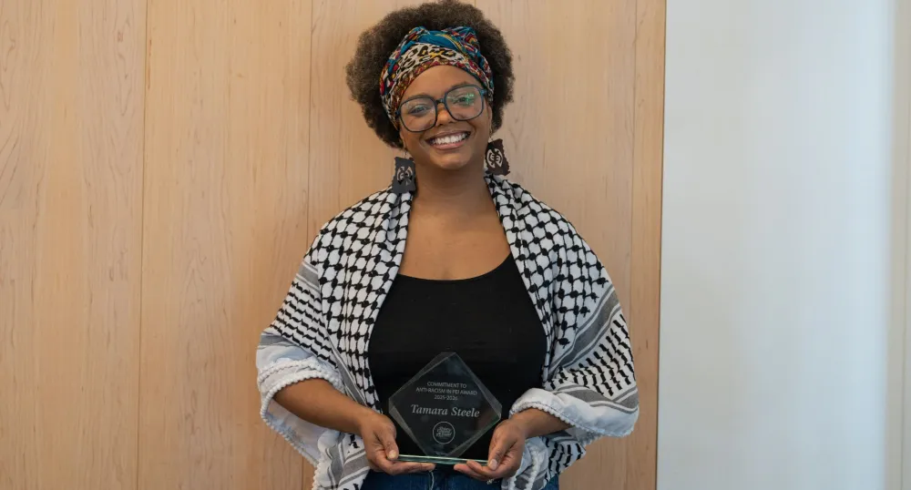 A smiling Black woman holds her award.