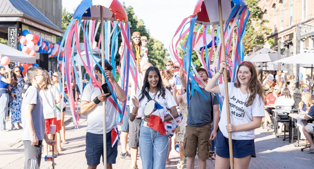 Some youth celebrate National Acadian Day in the street with bright red, white and blue colors.