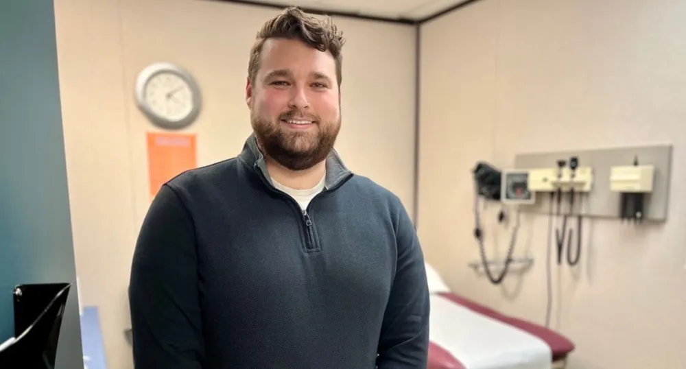 Un homme sourit dans une chambre d'hôpital.