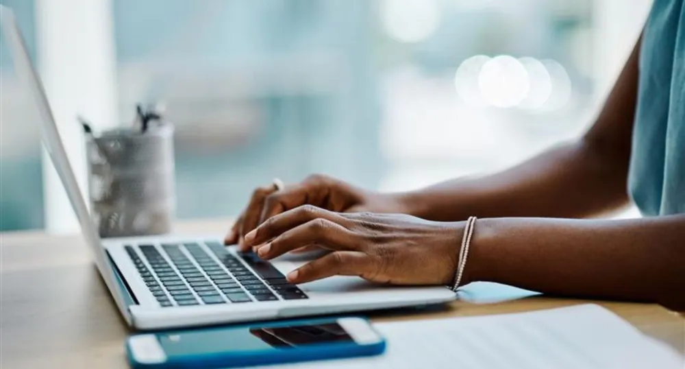 A Black woman types on a computer.