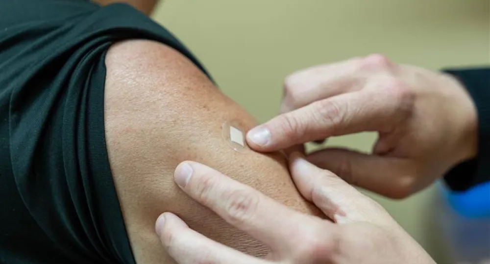 A doctor applies a bandaid to a person&#039;s arm after vaccination.