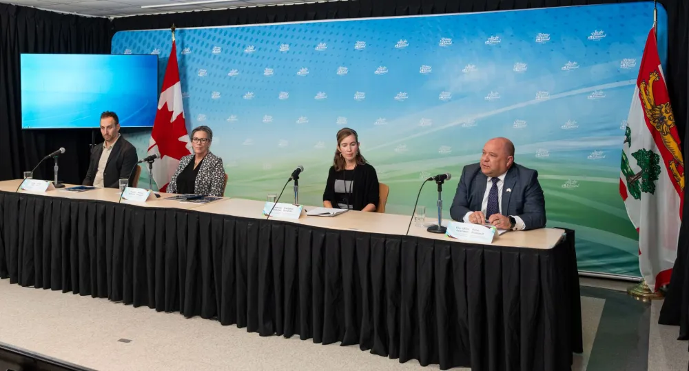 Deux hommes et deux femmes sont assis à une longue table avec un décor coloré.