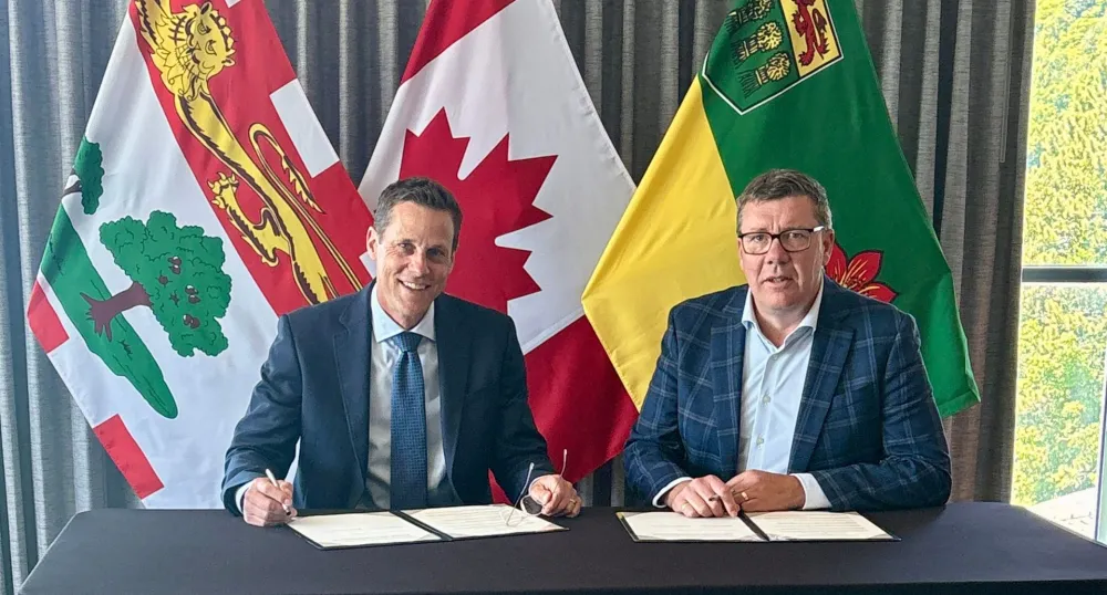 Le premier ministre Lantz et le premier ministre Moe sont assis devant les drapeaux de l'Île-du-Prince-Édouard, de la Saskatchewan et du Canada.