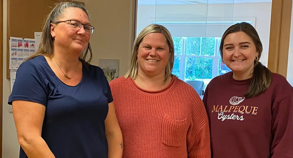 Three smiling women standing next to each other.