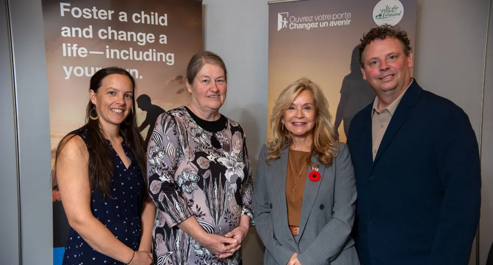 Three women and one man stand in front of the foster campaign posters.