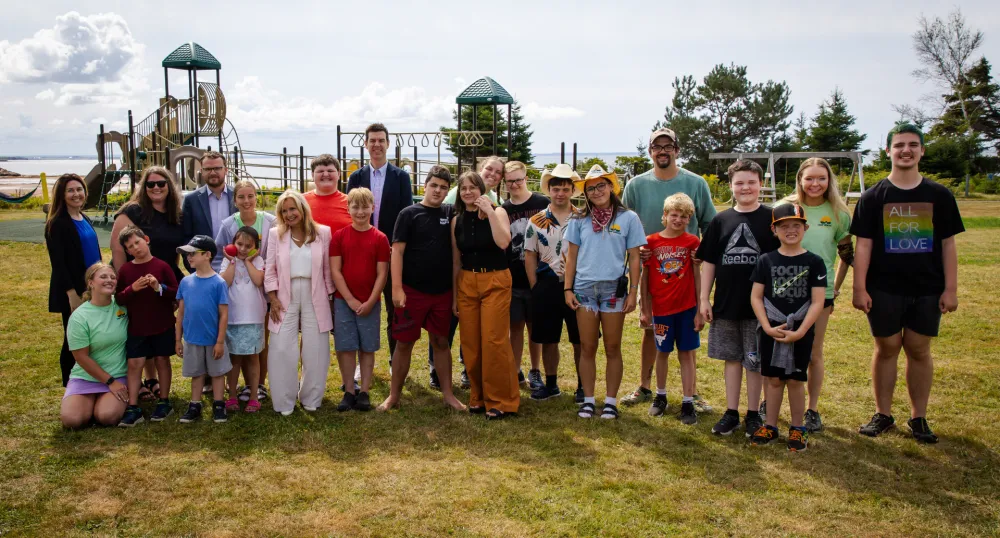 Les enfants et les adultes se rassemblent devant le terrain de jeux au Camp Gencheff.