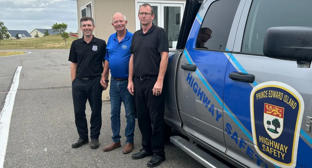 Three men stand in front of a Highway Safety Truck.