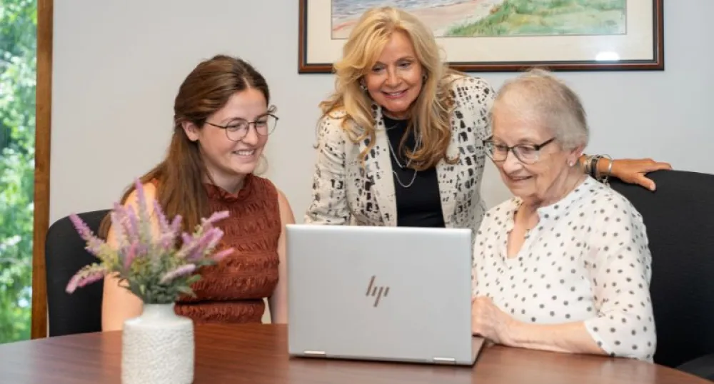 Une femme âgée et deux autres femmes se rassemblent autour d'un ordinateur.