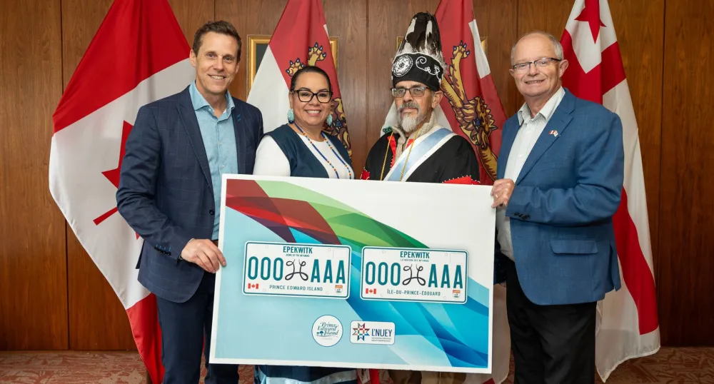 Quatre personnes se tiennent derrière un panneau représentant le nouveau modèle de plaque d'immatriculation.