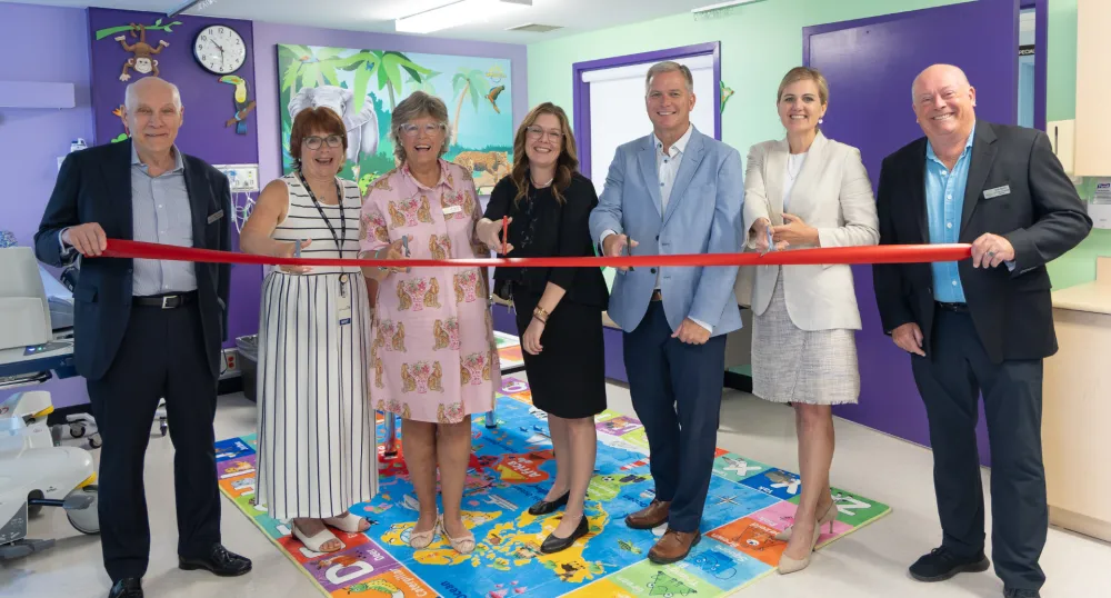 Sept personnes se sont rassemblées dans une zone Smilezone colorée pour couper le ruban cérémoniel.