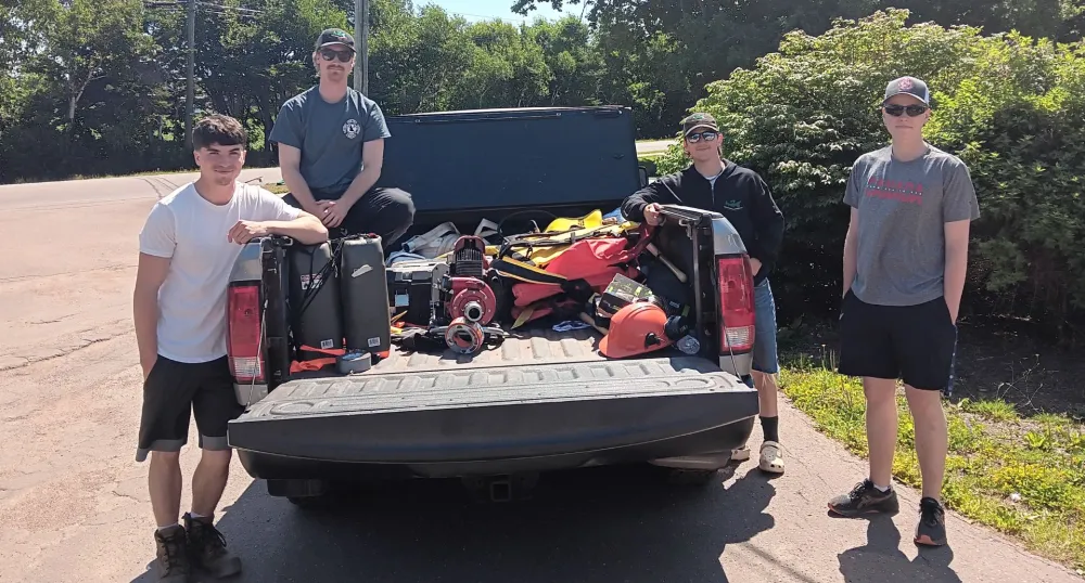 Quatre étudiants en lutte contre les incendies se tiennent autour d'un camion équipé de matériel de lutte contre les incendies.