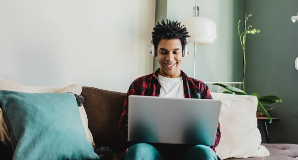 Un jeune homme portant un casque et regardant un ordinateur portable