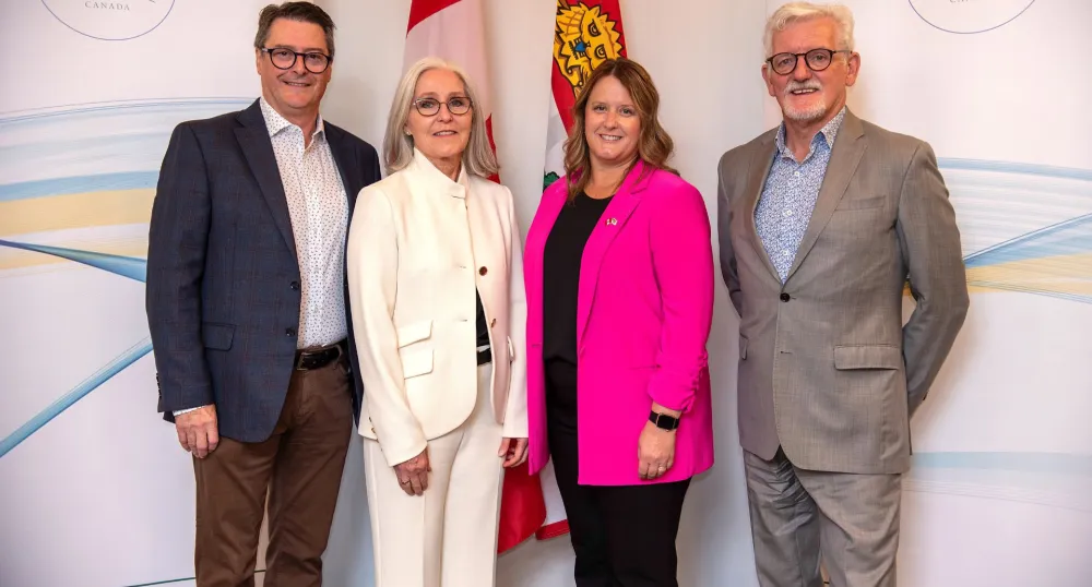 Les quatre personnes citées se tiennent côte à côte après l'annonce.