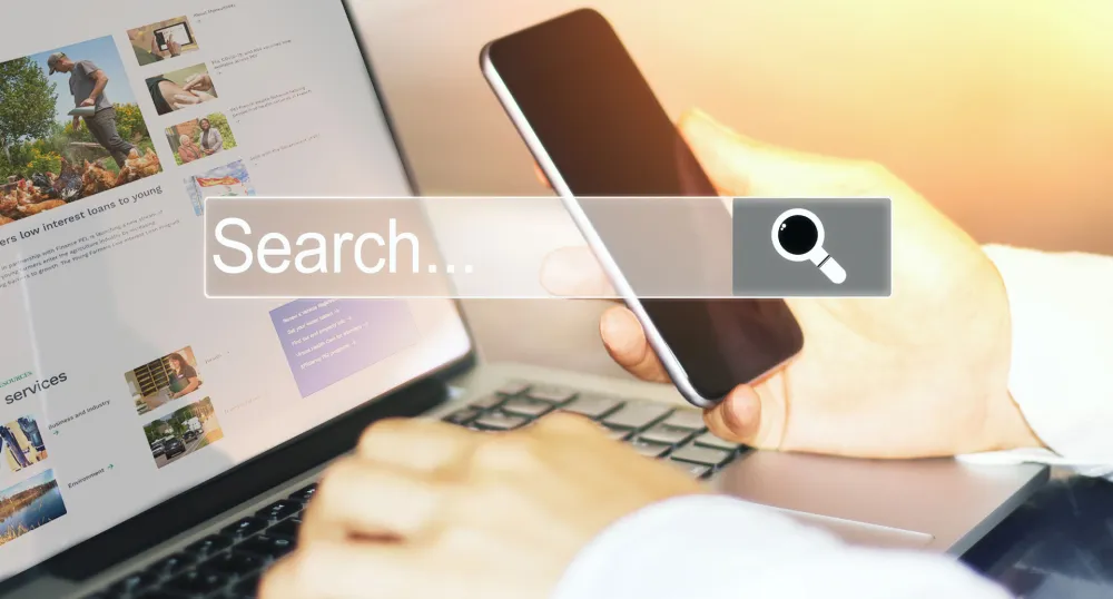 Image of individual using a laptop with text that reads "search"