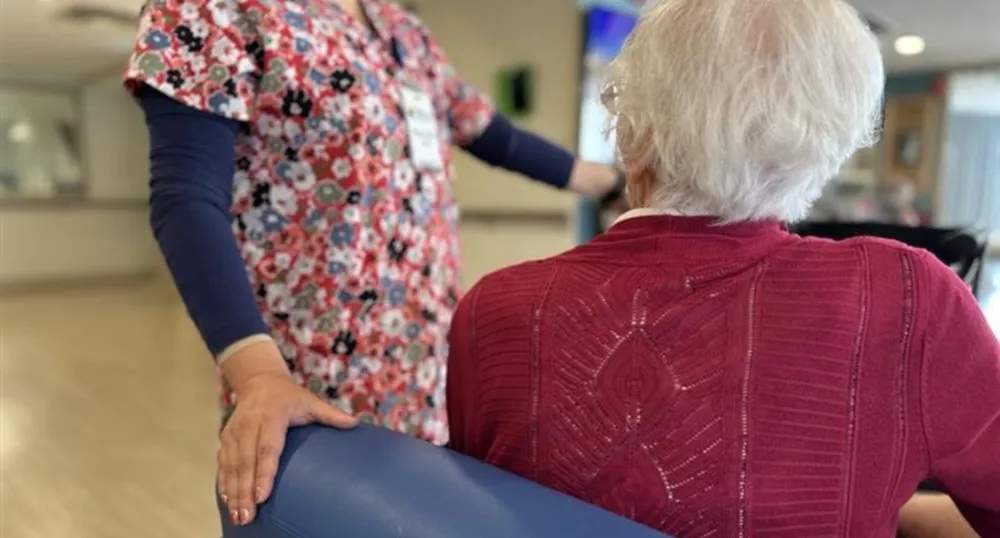 Un travailleur en soins de longue durée se tient à côté d'une femme âgée.