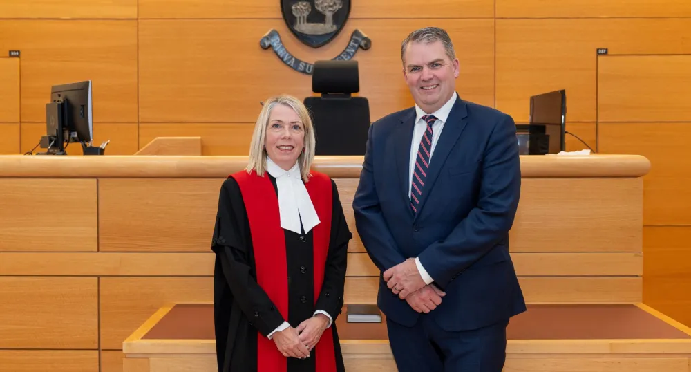 The new judge and the minister stand next to each other in the courthouse.