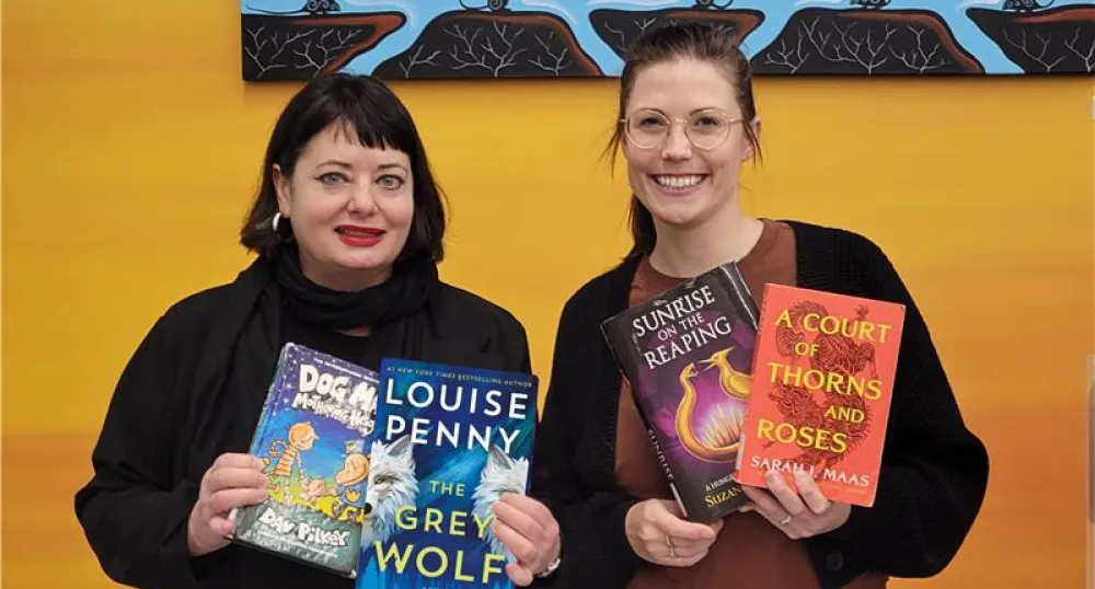 Two women librarians hold several books from the top pics list.