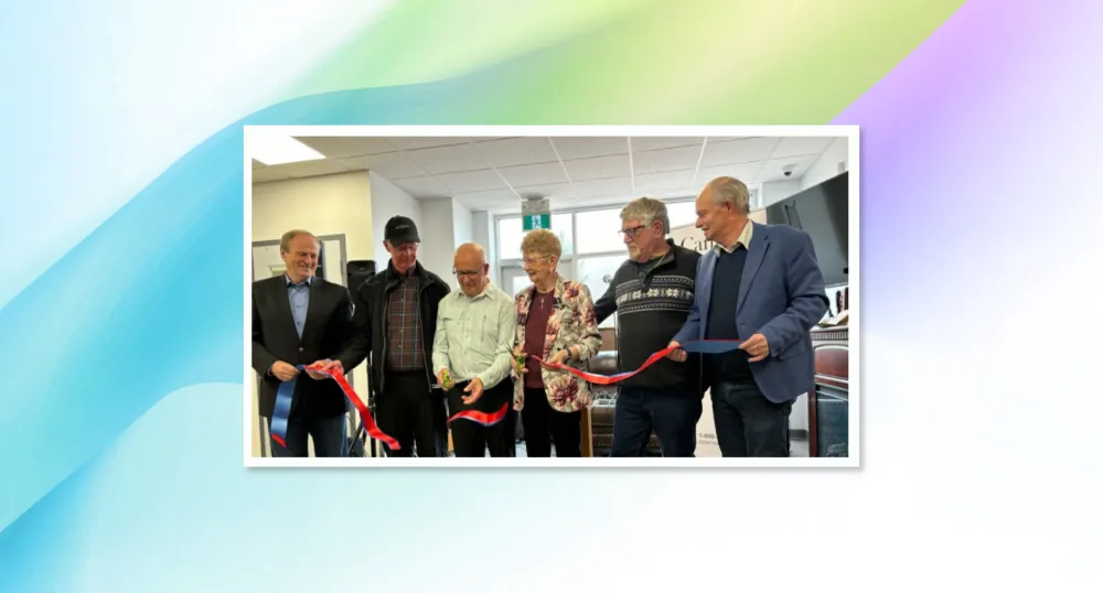 image of six people in a room standing shoulder to shoulder and one person is cutting a ribbon held by all of them