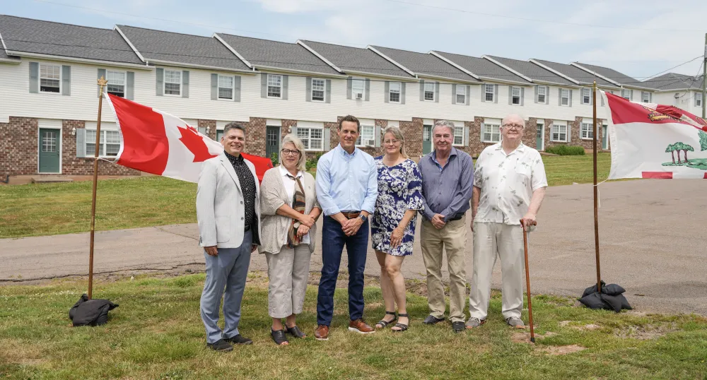 Six personnes debout devant des logements