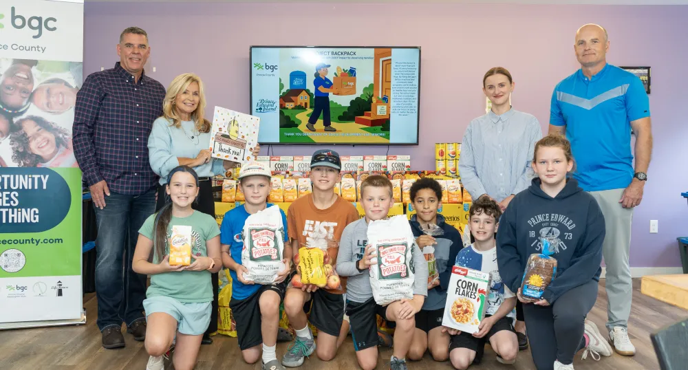 A group of adults and children holding PEI potato bags/