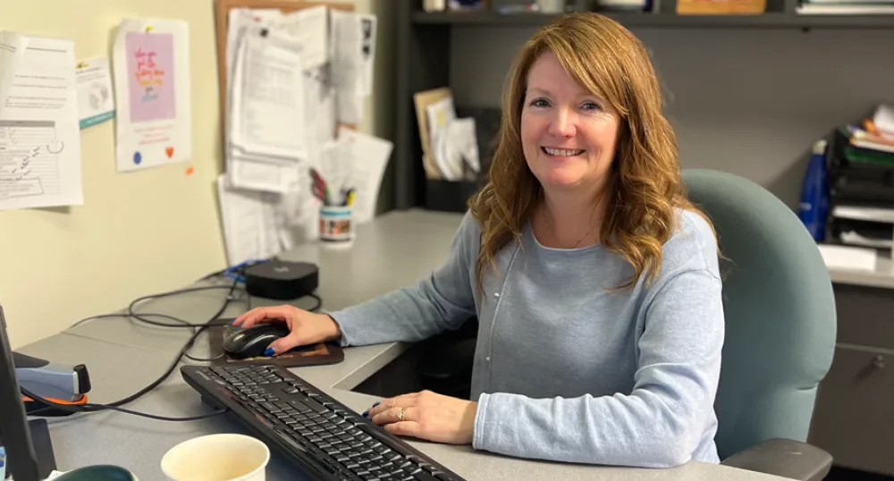 image of a person siting behind a work desk in an office with a hand on a computer mouse
