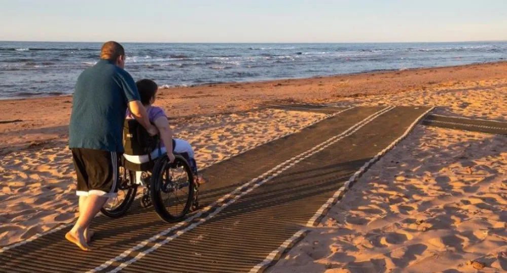 Individuals using accessibility mat on local beach