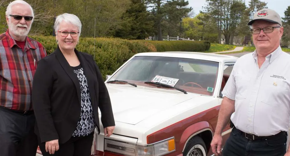 Three people standing in front of car