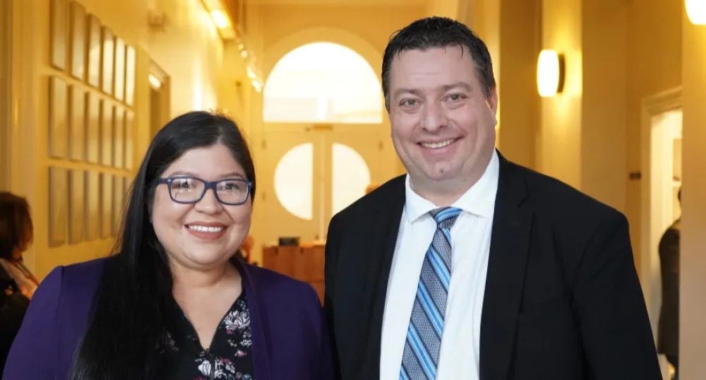 Two people standing side by side in a hallway