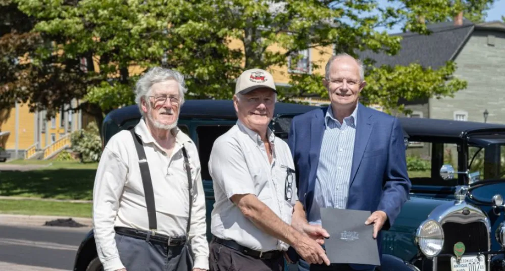 image de trois personnes debout devant une voiture ancienne