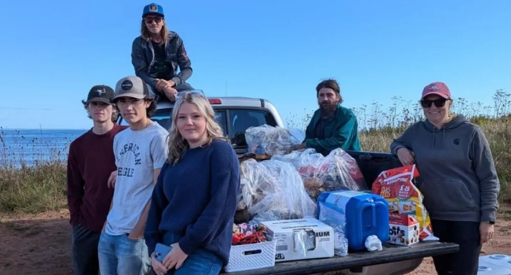 image d'un groupe de personnes assises et debout autour d'un camion garé près du rivage