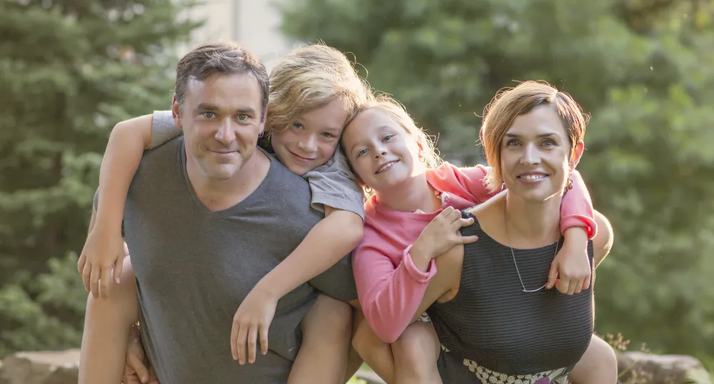 Bonnie Stewart and her partner Dave Cormier post while giving their children piggy-back rides