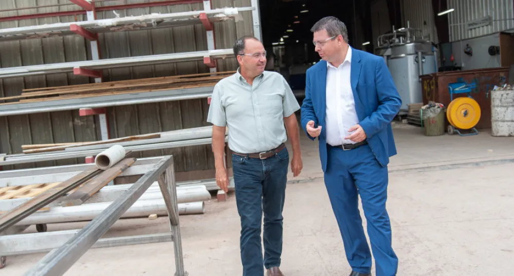 Two men standing inside a fabrication yard work area