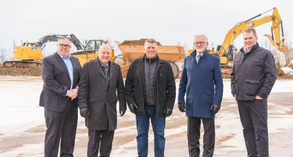 image of a group of people standing shoulder to shoulder in front of constructions equipment