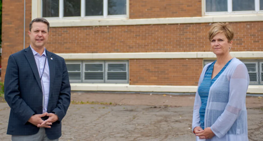 Image of two people standing in fromt of a brick building