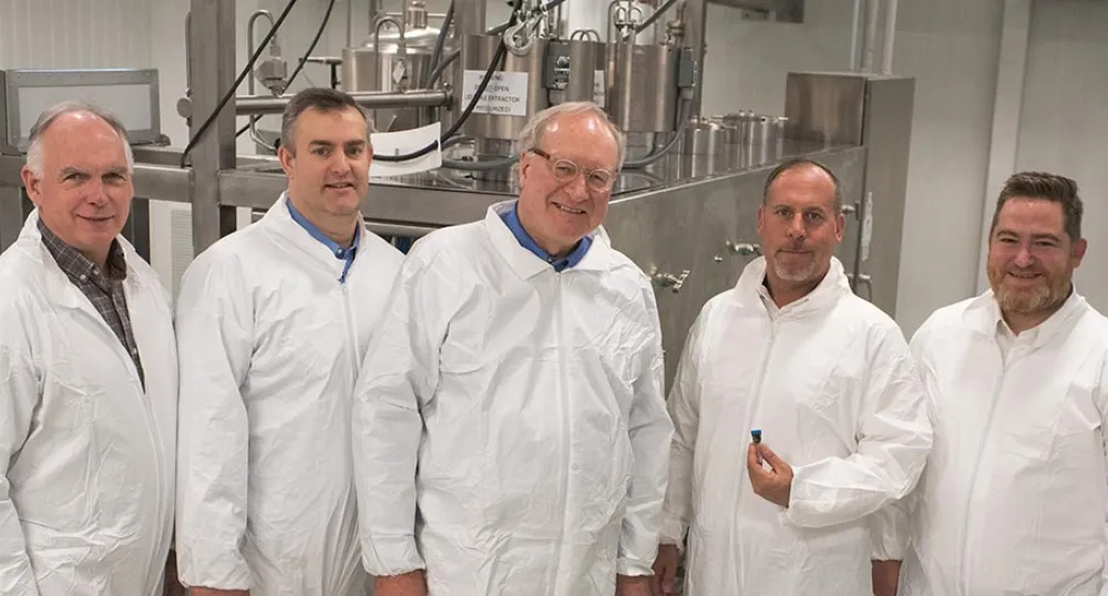 Five people lined up beside each other in front of extraction equipment