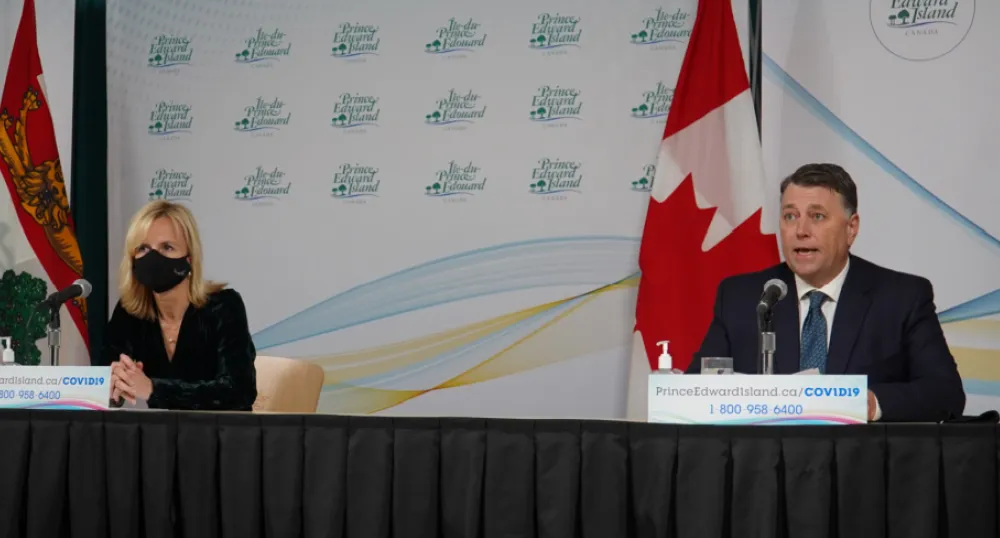image of two people wearing masks while sitting at a news conference table