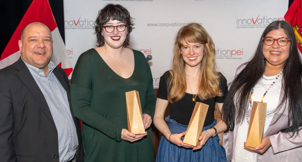 image de quatre personnes debout côte à côte, certaines détenant de petites récompenses