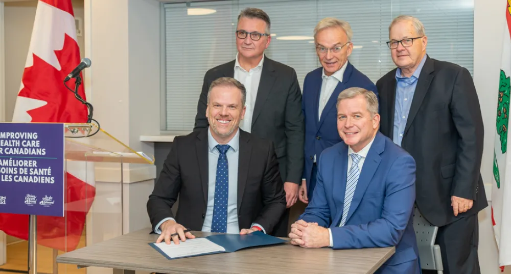 image of five people at a table signing a document